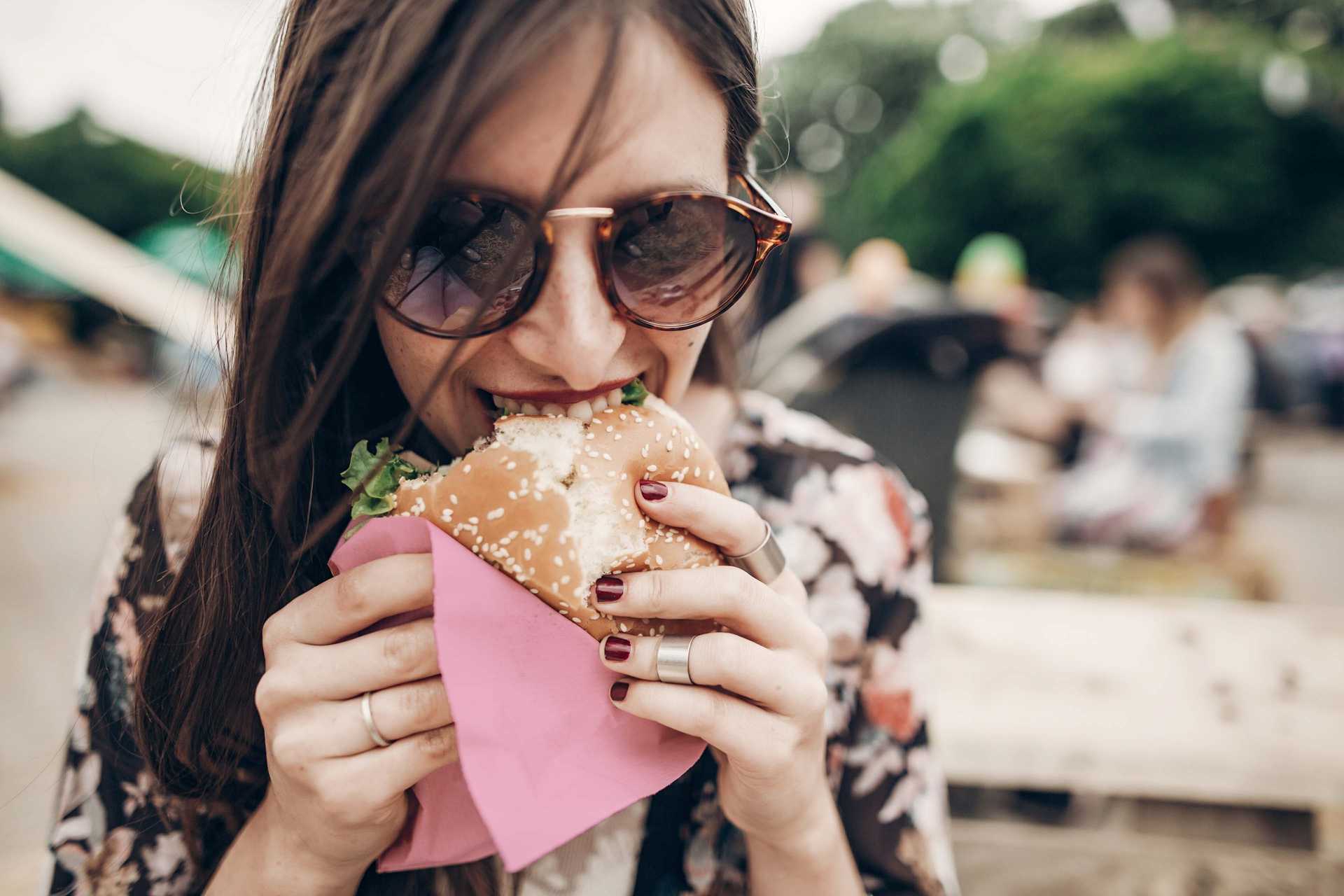 Hamburger yiyen genç gözlüklü kadın